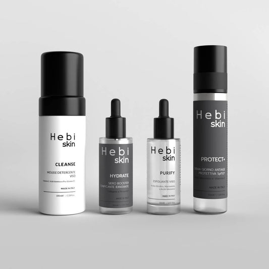 Quattro prodotti HBSKN Hebi Skin su sfondo grigio: CLEANSE mousse, HYDRATE siero, PURIFY esfoliante, PROTECT+ crema SPF50+