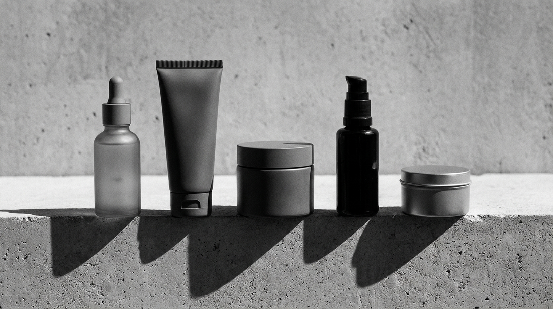 Linea skincare completa da uomo: cinque prodotti viso disposti in griglia su superficie di cemento