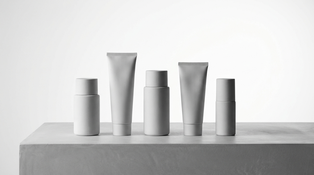 Flaconi skincare uomo senza marca allineati per confronto, still life editoriale monocromo HBSKN