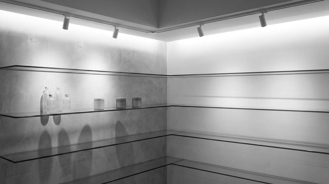 Selezione corta di skincare maschile in flaconi airless monocromi su uno scaffale minimale di una profumeria premium