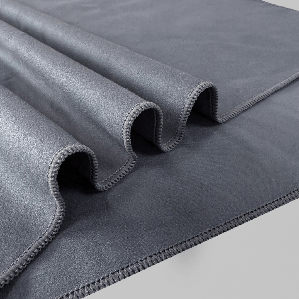Asciugamano in microfibra grigio HBSKN arrotolato, dettaglio cucitura e texture