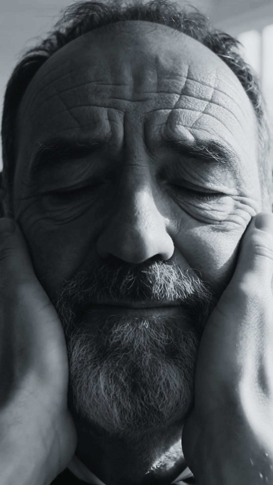 Un uomo adulto, il viso tra due mani, occhi chiusi — dal film LE MANI