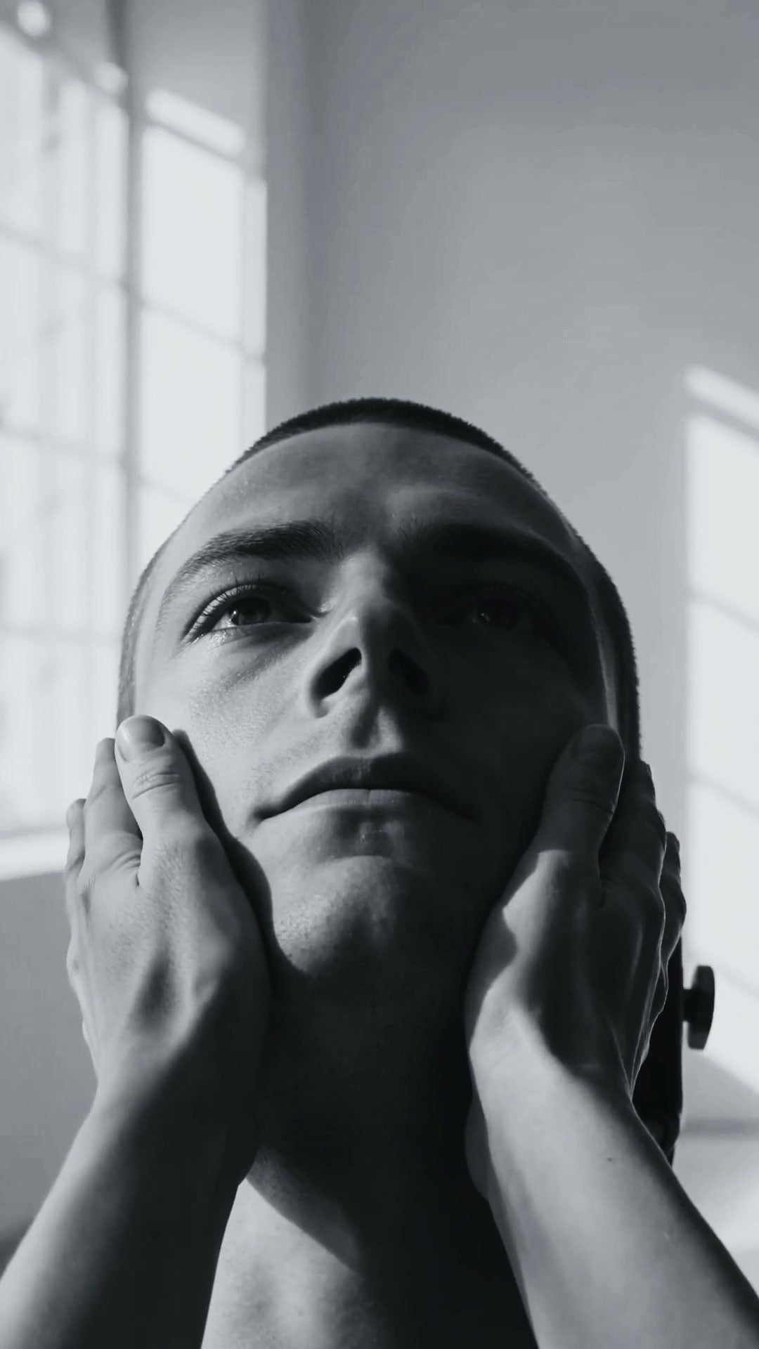 Un uomo giovane, il viso tra due mani, occhi chiusi — dal film LE MANI